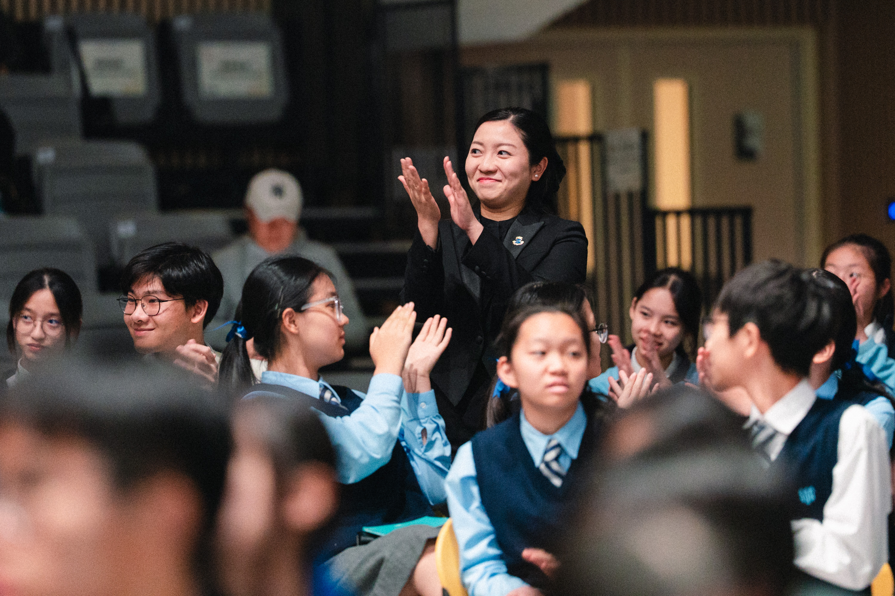 A conductor applauding among students at an HKVC event