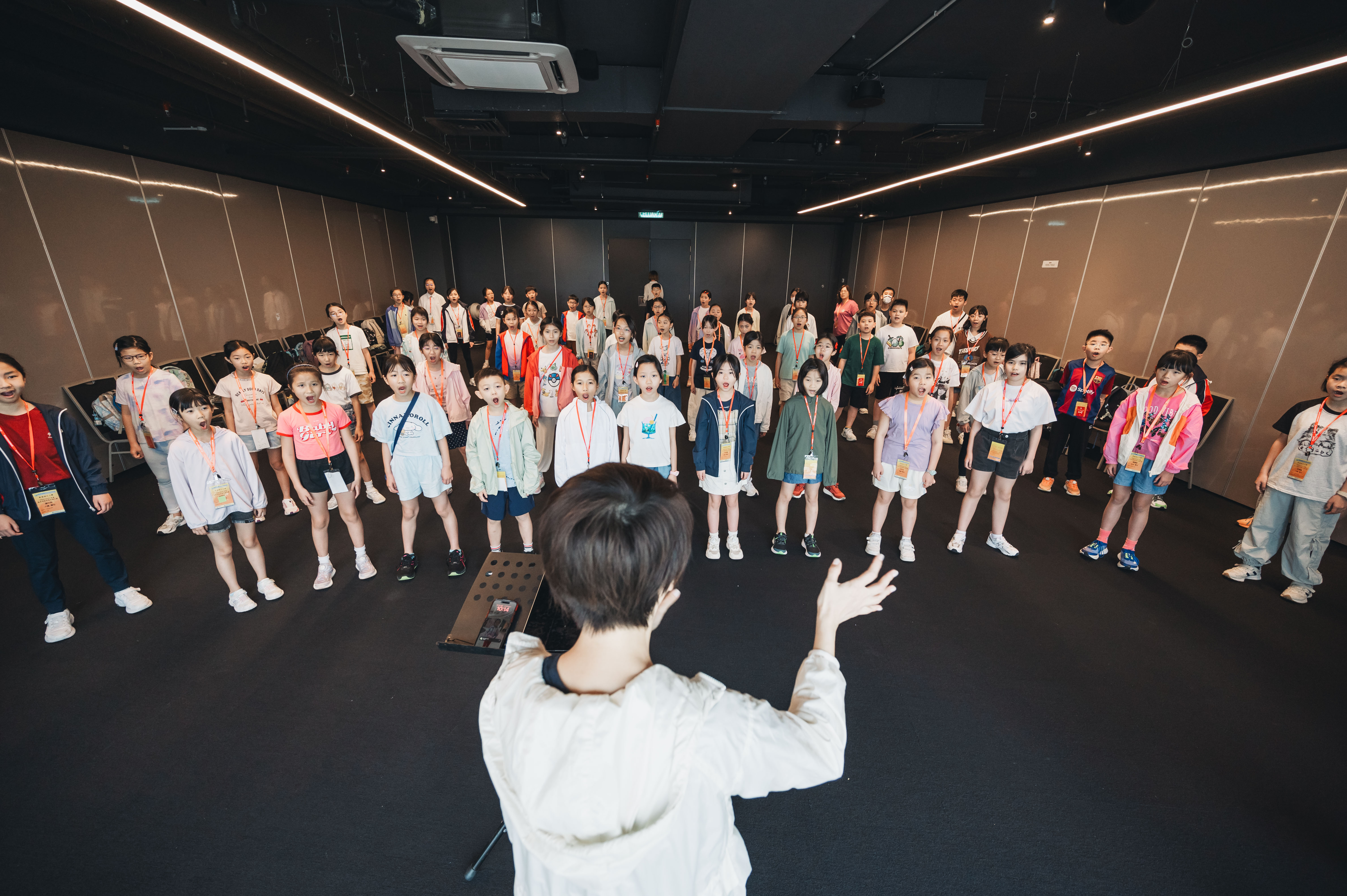 A conductor leads a large children's choir through a rehearsal during the Hong Kong–Malaysia school choir exchange in Kuala Lumpur