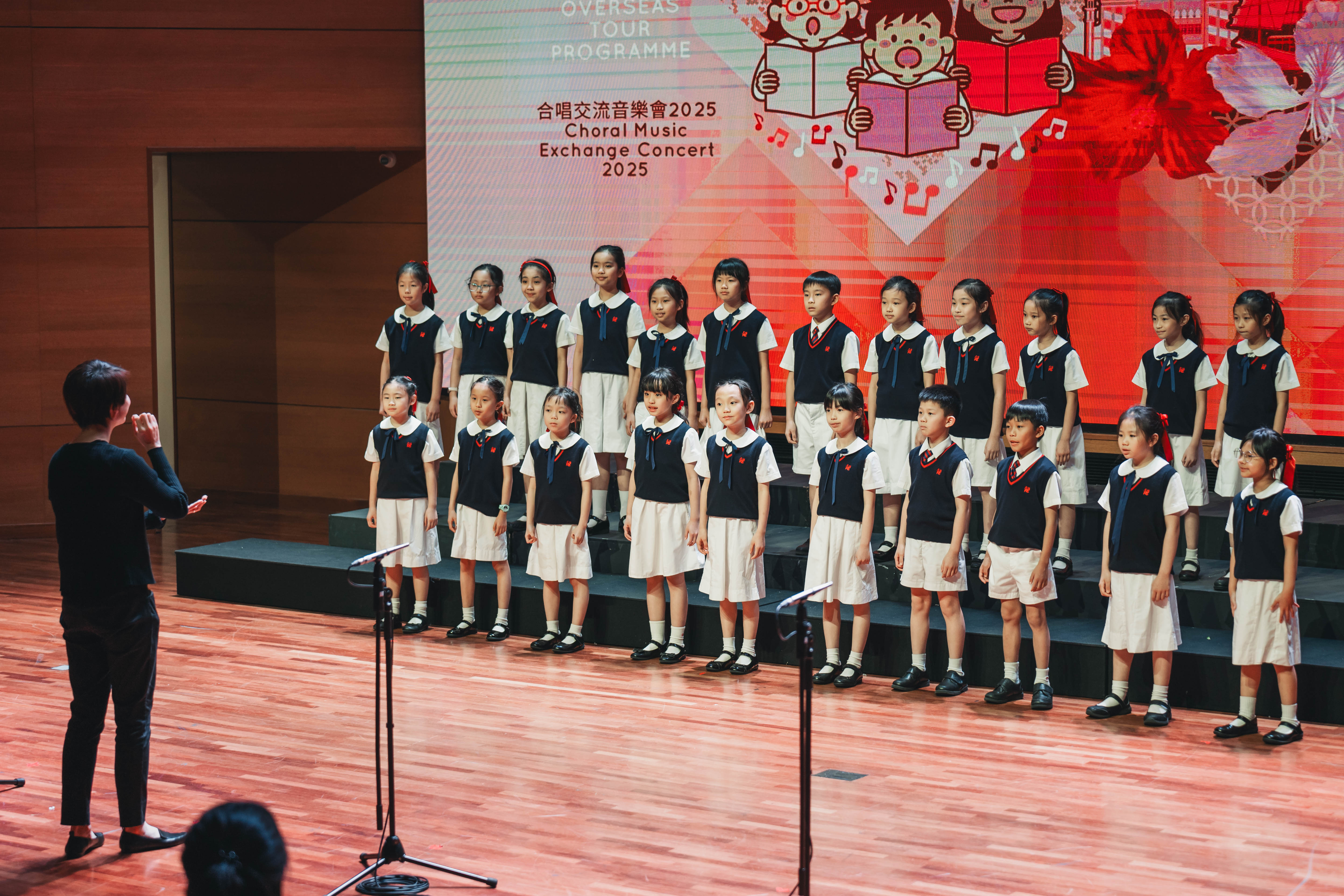 A uniformed school choir performs at the Choral Music Exchange Concert 2025 in Kuala Lumpur, with the event title on the LED wall behind them